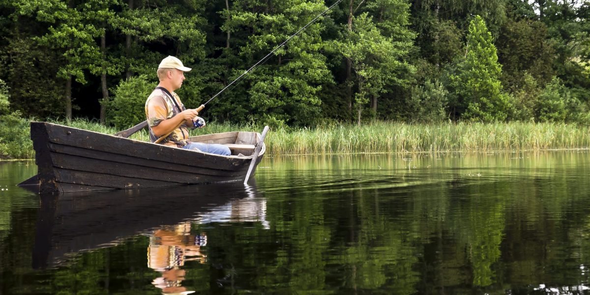 Fisherman,Is,Sitting,In,The,Old,,Wooden,Rowboat,And,Catching